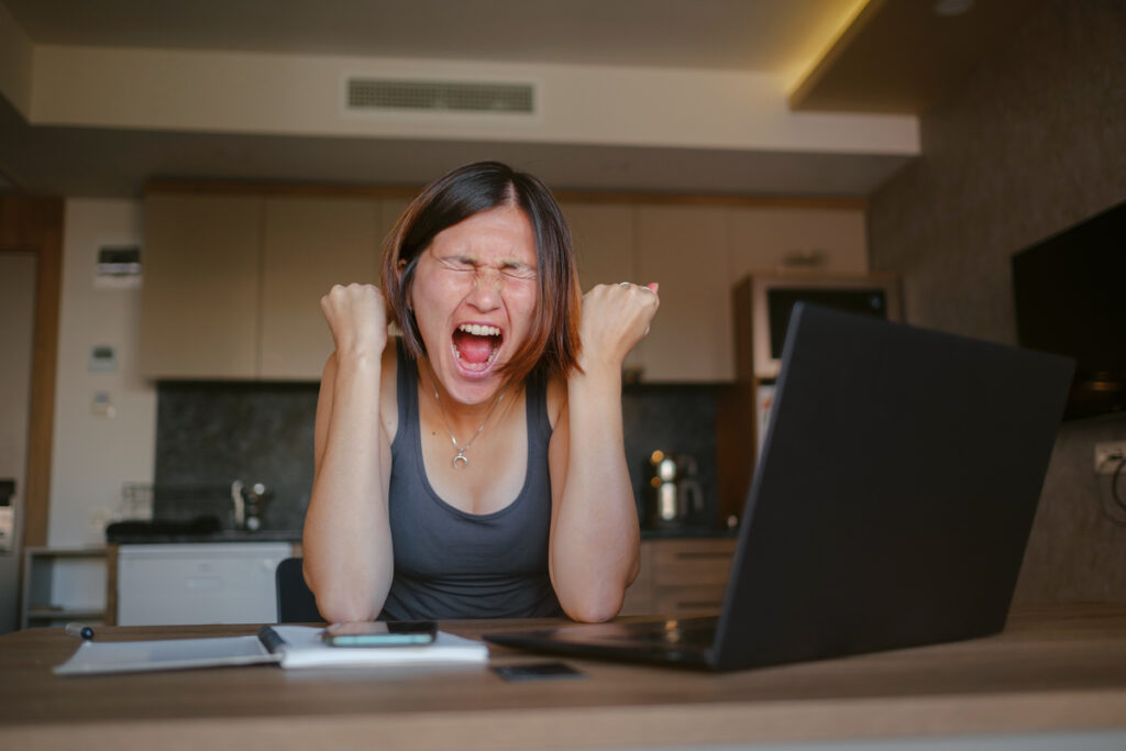 Молодая женщина радуется у компьютера