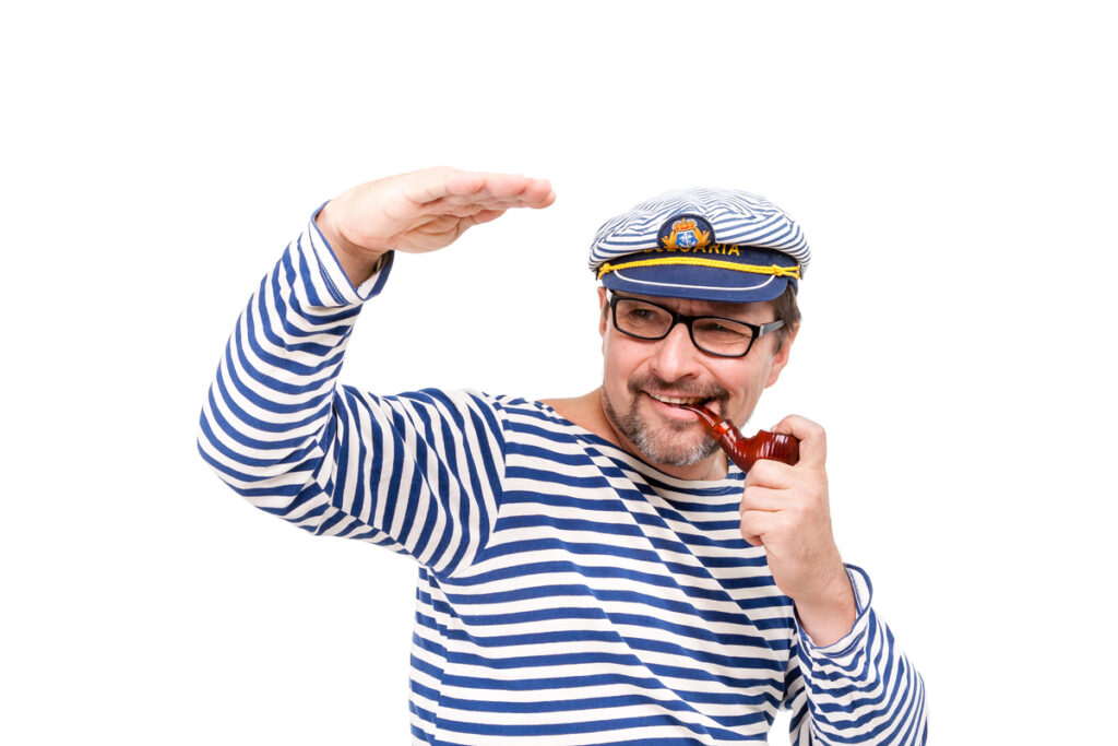 Мужчина-моряк в кепке с курительной трубкой