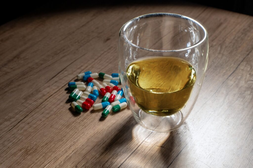 Разноцветные таблетки и алкоголь на столе