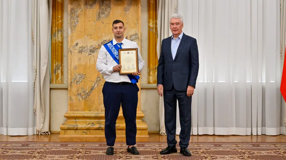 Мэр Москвы Сергей Собянин награждает водителя электробуса Романа Виноградова, который в этом году победил на конкурсе «Московские мастера»