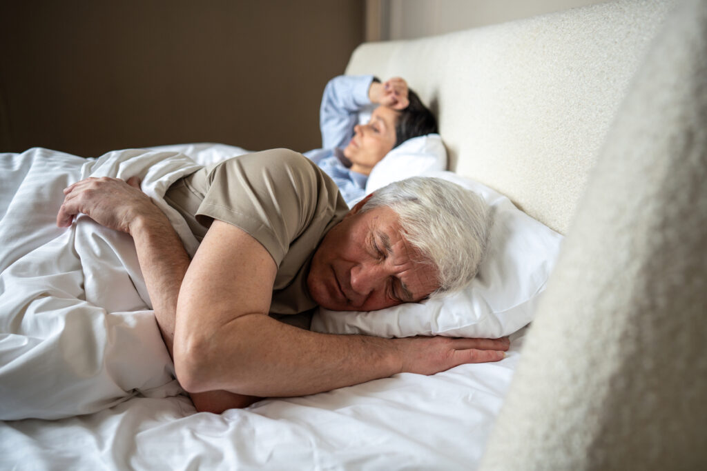 Пожилая пара спит в постели

