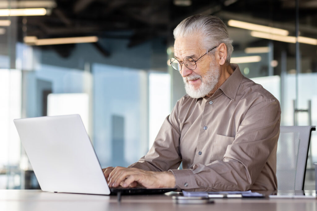 Пожилой сотрудник работает за ноутбуком
