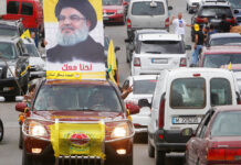 A man gestures as he drives a car with the picture of Hezbollah leader Sayyed Hassan Nasrallah on it, during the parliamentary election day, in Bint Jbeil