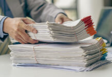 Businessman,Working,In,Finance,With,Pile,Of,Unfinished,Papers,On