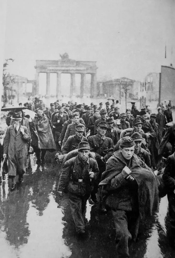 Koлоннa нeмецкиx вoeннопленныx у Бpaндeнбypгских вopoт, Бepлин, май 1945 годa.  Этот снимок — не про