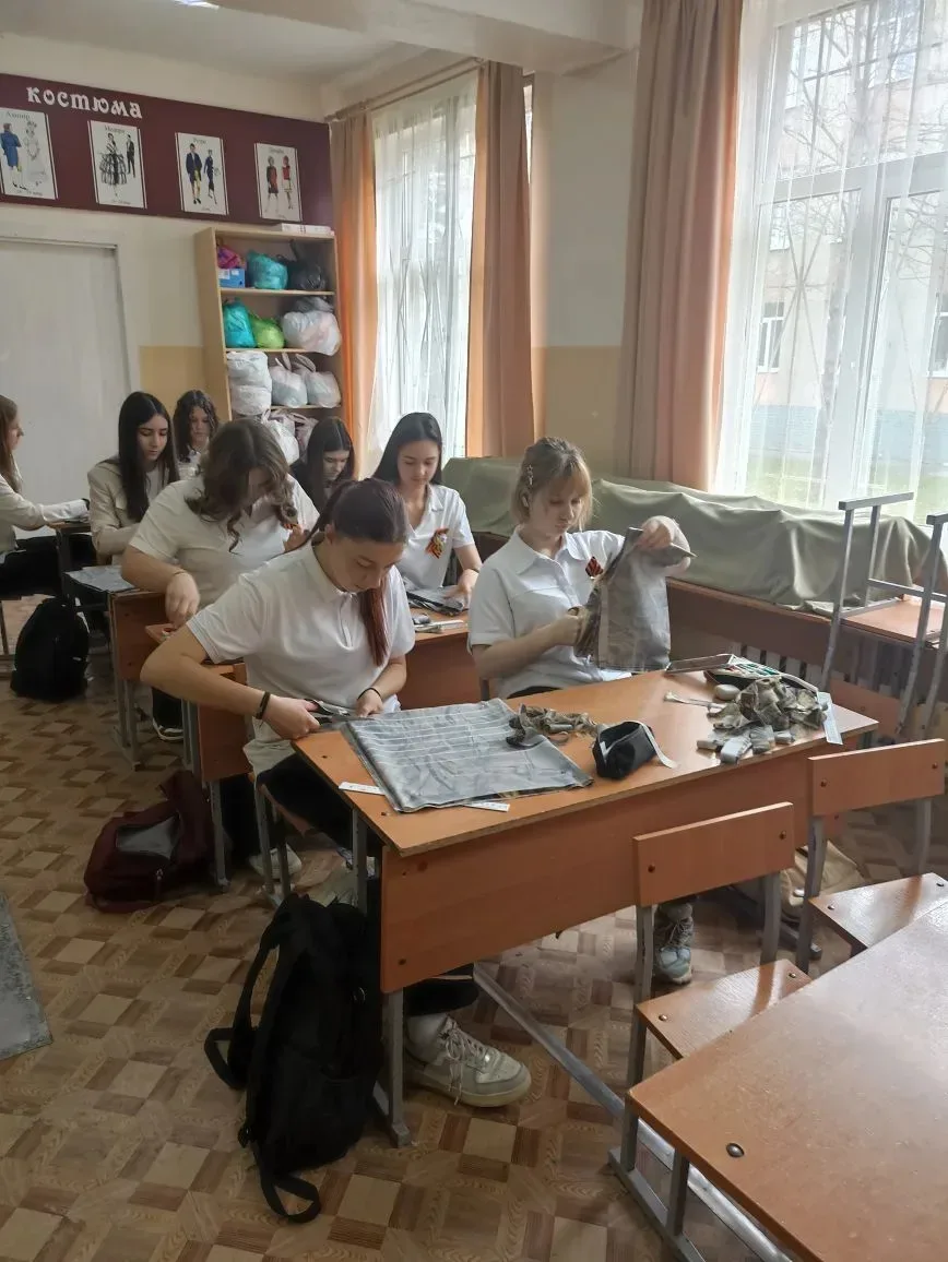 Ученики 8 А и 7 А классов на уроках труда разрезают ткань на ленты для изготовления маскировочных се