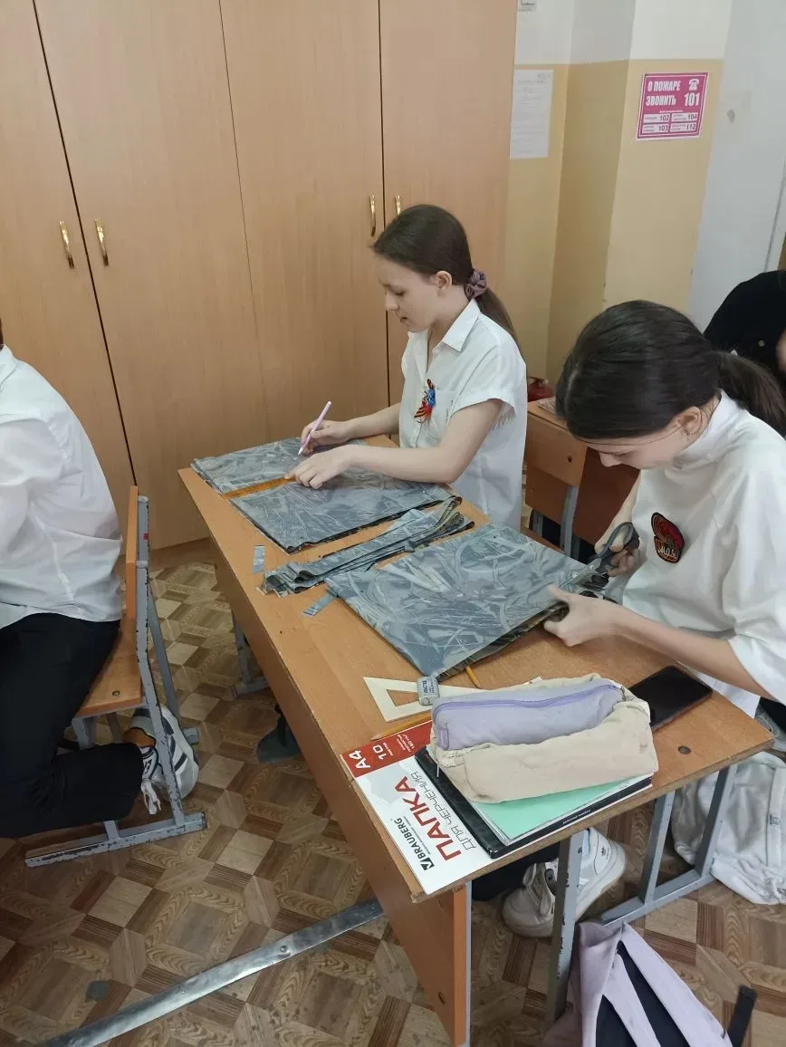 Ученики 8 А и 7 А классов на уроках труда разрезают ткань на ленты для изготовления маскировочных се