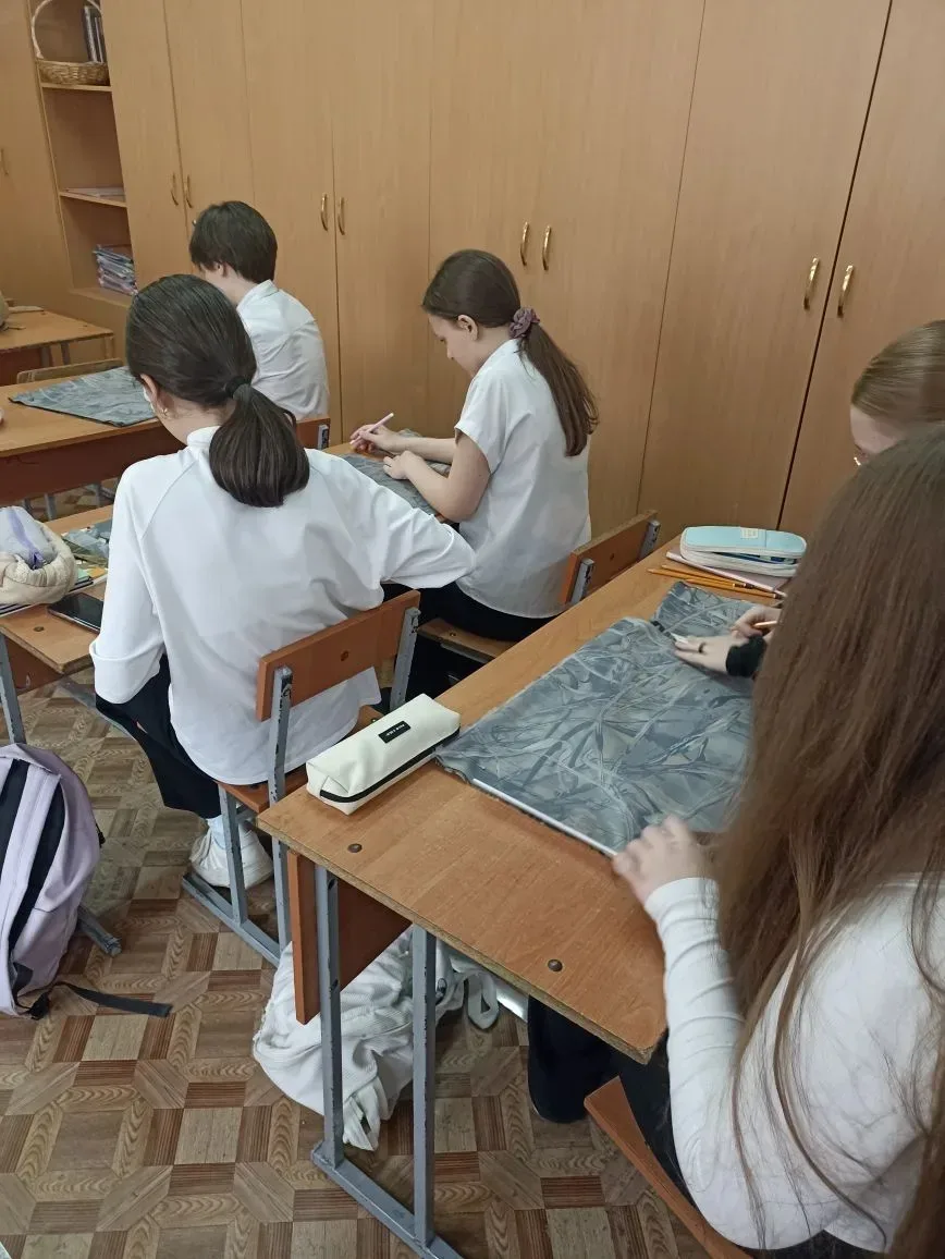 Ученики 8 А и 7 А классов на уроках труда разрезают ткань на ленты для изготовления маскировочных се