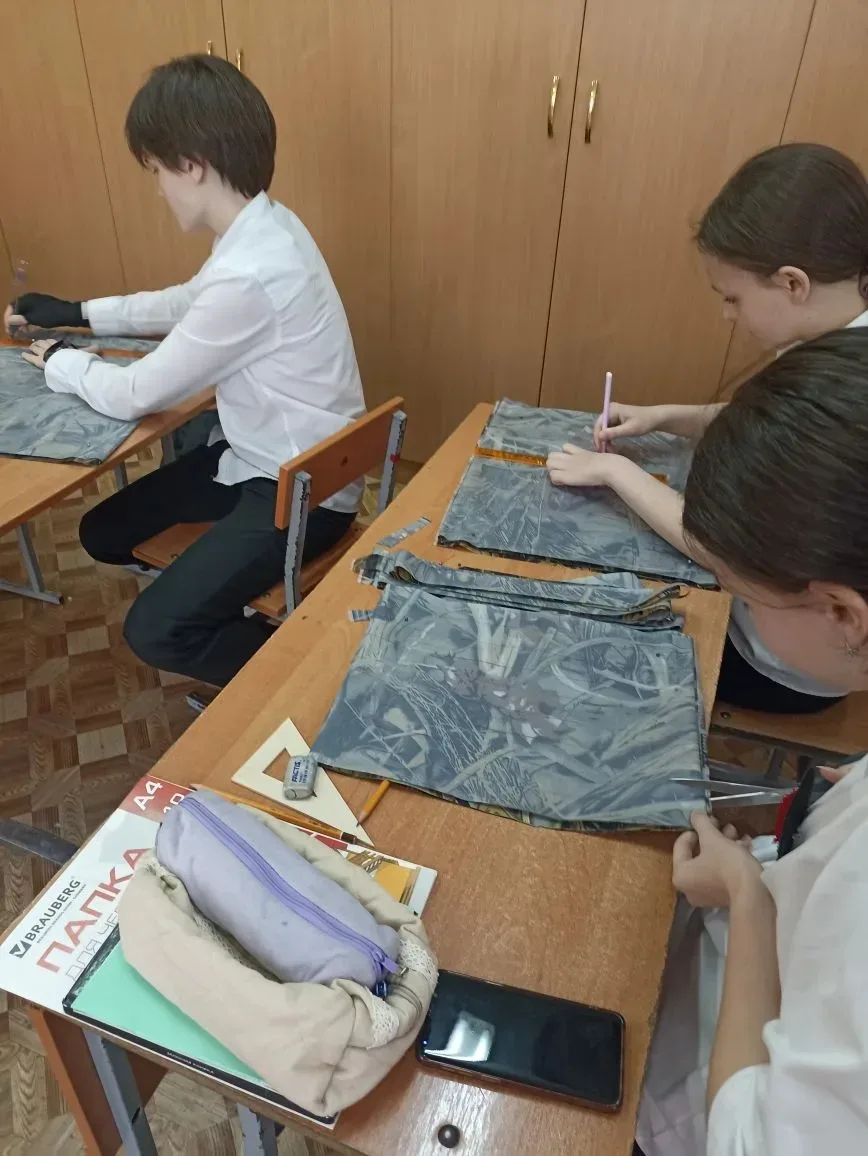 Ученики 8 А и 7 А классов на уроках труда разрезают ткань на ленты для изготовления маскировочных се